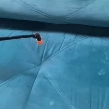 Bico extrator passando sobre o assento de um sofá azul durante a higienização